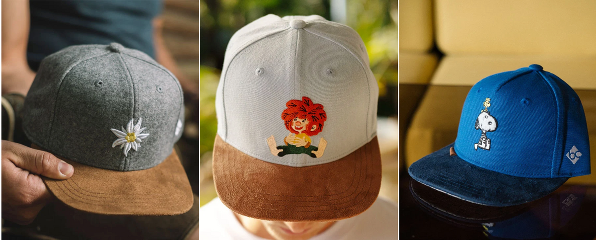 Drei Caps mit Stickereien: ein Edelweiß, eine rothaarige Comicfigur und Snoopy.