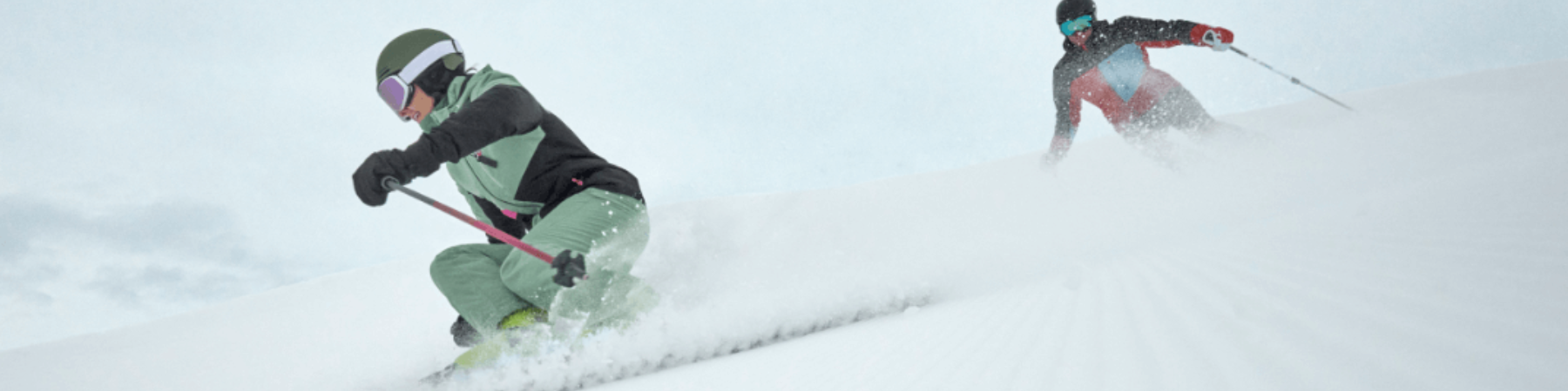 Zwei Skifahrer fahren Piste hinunter