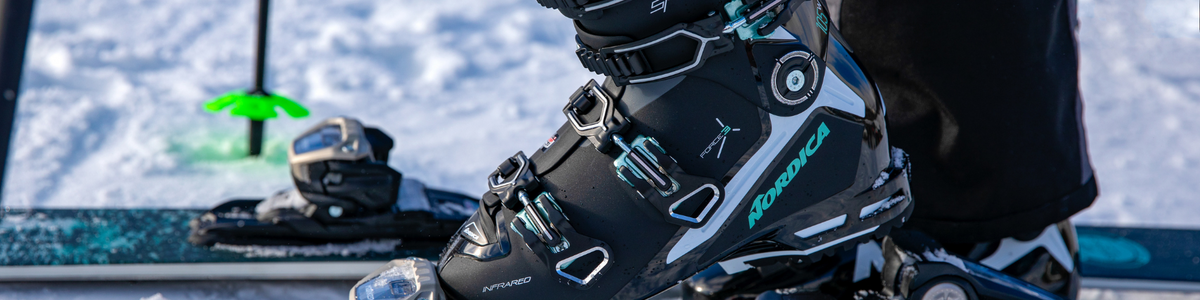 Schwarz-türkiser Nordica-Skischuh in der Skibindung, im Hintergrund Schnee