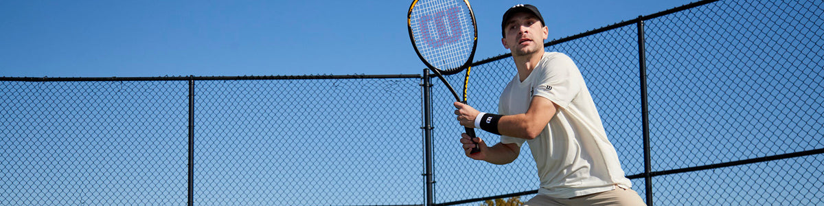 Mann hält Tennisschläger in der Hand und spielt Tennis.