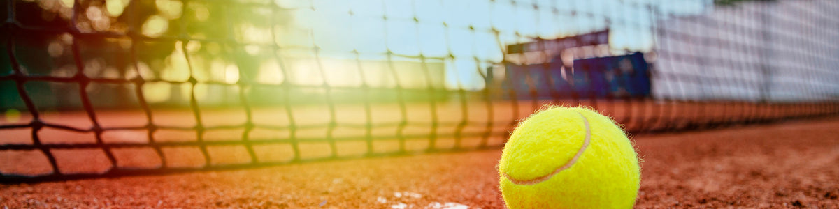 Tennisball auf dem Sandplatz vor dem Netz