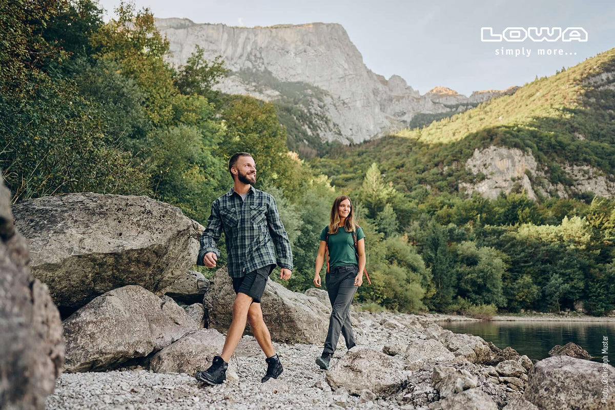 Wanderpaar in Wanderschuhen auf einem steinigen Weg an einem Bergsee