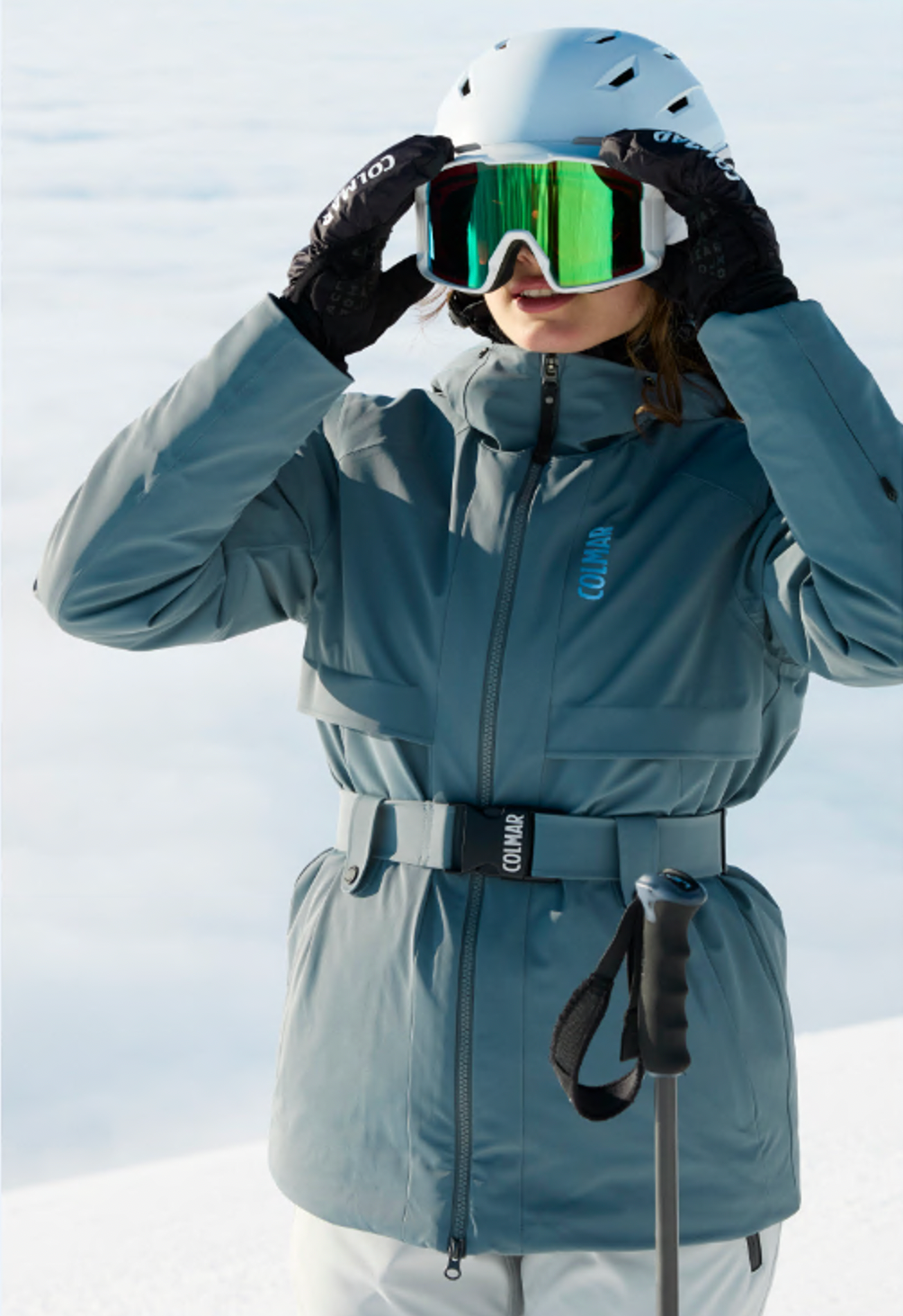 Skifahrerin in blaugrauer Skijacke setzt die Skibrille auf