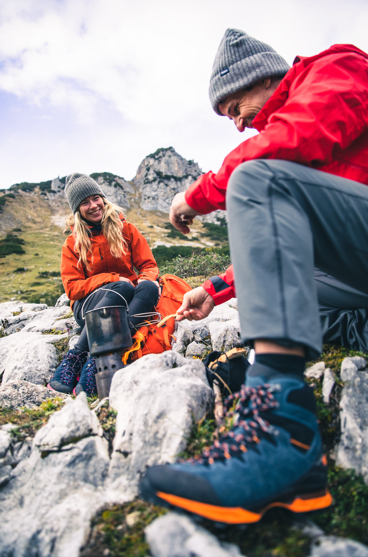 Zwei Wanderer in Outdoorjacken und Bergschuhen rasten auf Felsen
