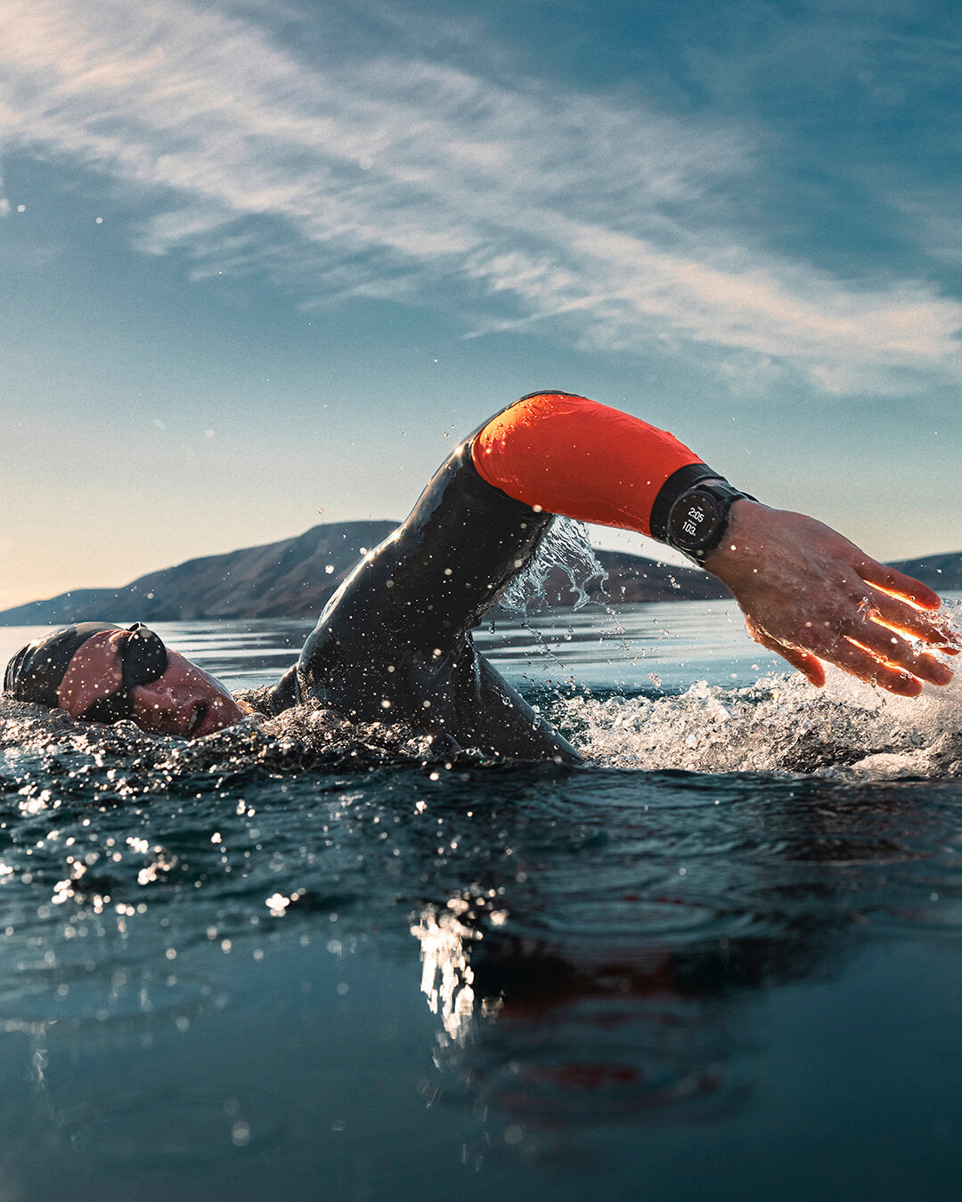 Triathlet im Neoprenanzug krault mit Sportuhr durch einen See
