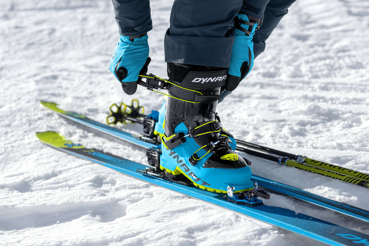 Mann schließt seine blauen Dynafit Skischuhe